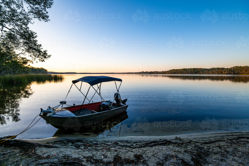 small boat on body of water at dusk - Australian Stock Image