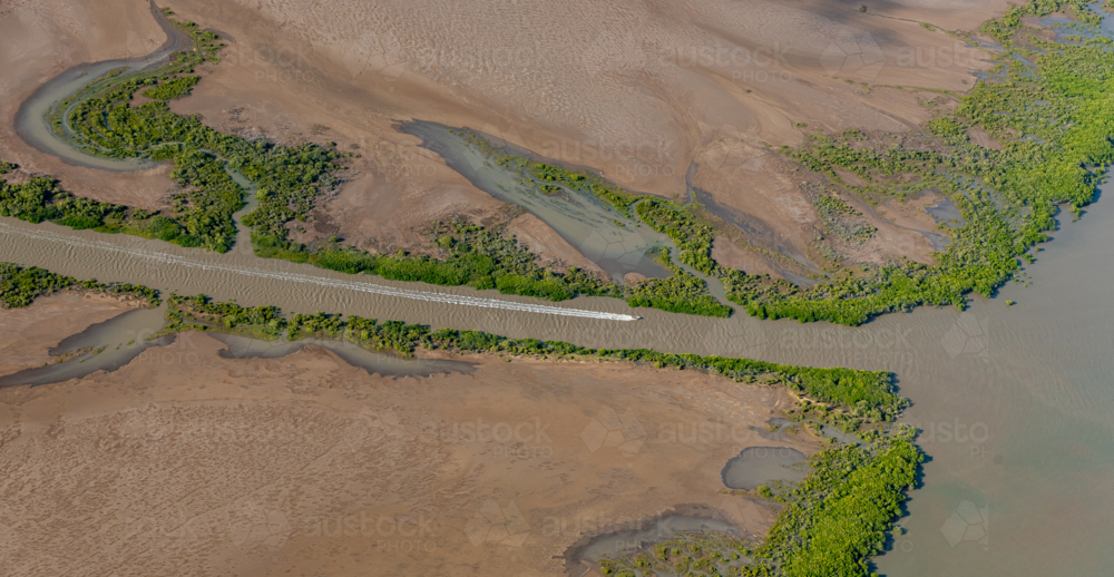Small boat travels along the rivers of Balaclava Island leaving a visible wake behind it - Australian Stock Image