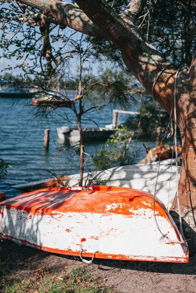Small boat under trees on the bank of a river - Australian Stock Image