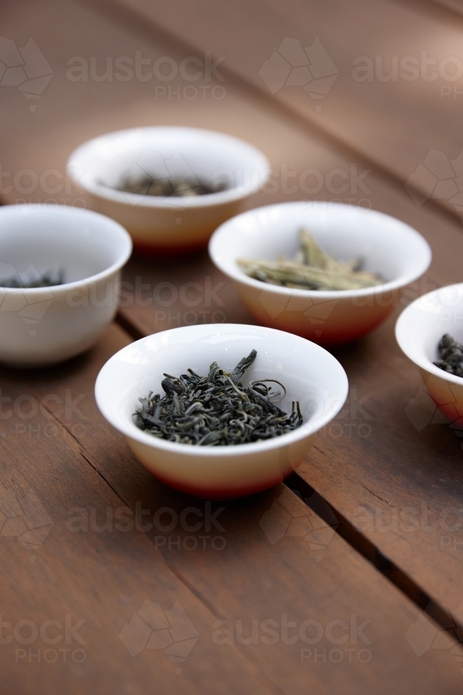 Small bowls of tea leaves on table - Australian Stock Image