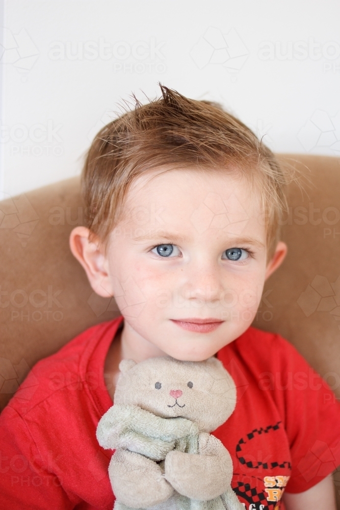 Small boy holding a well loved soft toy - Australian Stock Image