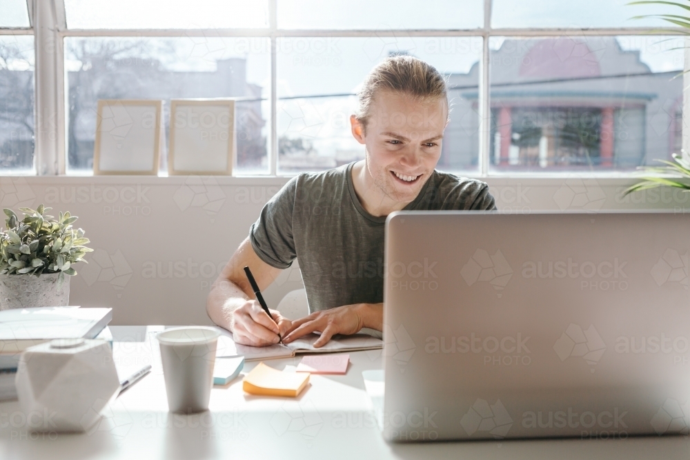 Small business owner working at his desk in a bright office - Australian Stock Image