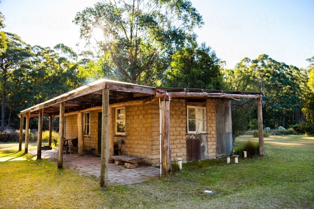 Small cabin with chimney and verandah in clearing - Australian Stock Image