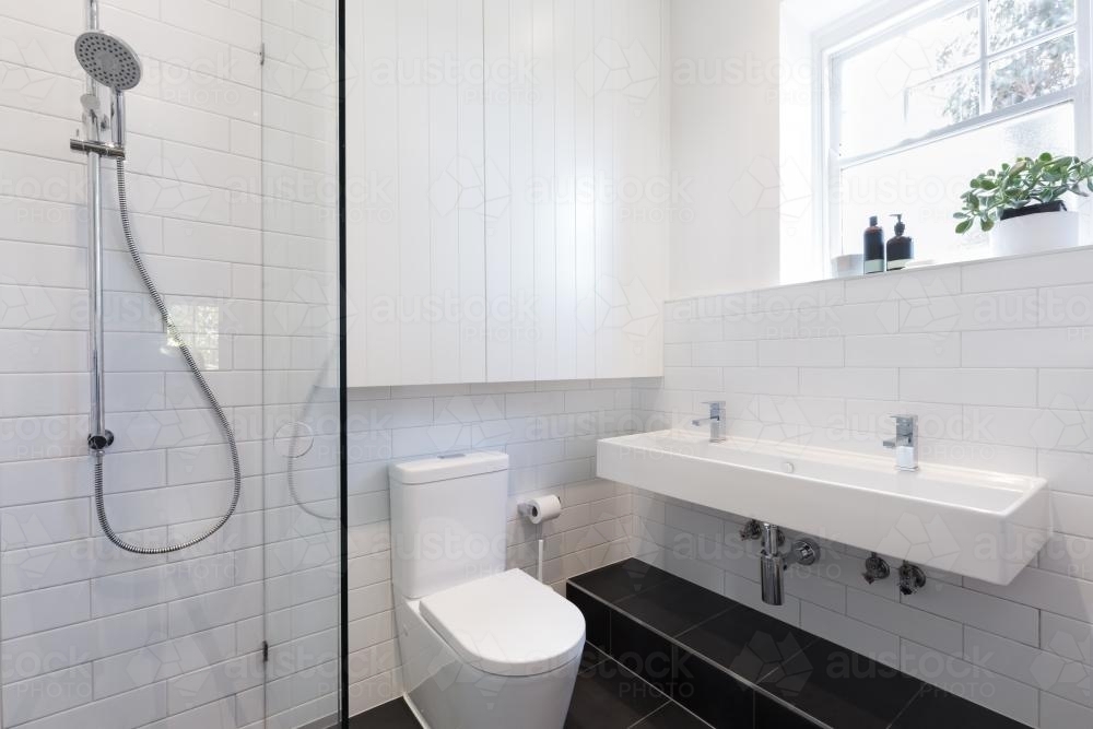 Small ensuite bathroom with white tiling laid in a brick pattern - Australian Stock Image