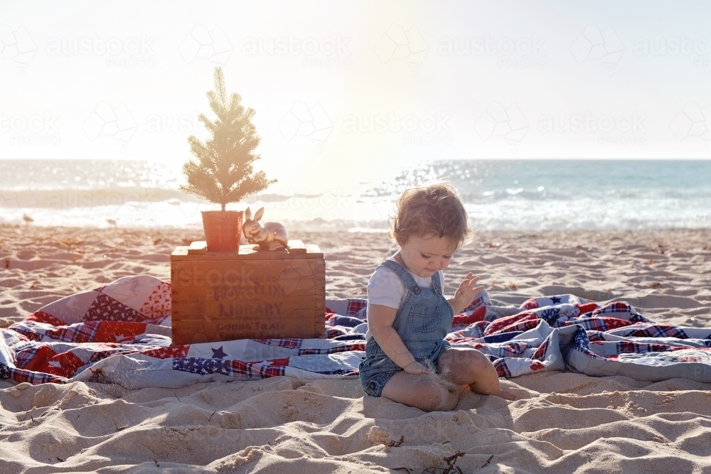 Small Girl Sitting In a Christmas Themed Setting At The Beach At Sunset - Australian Stock Image