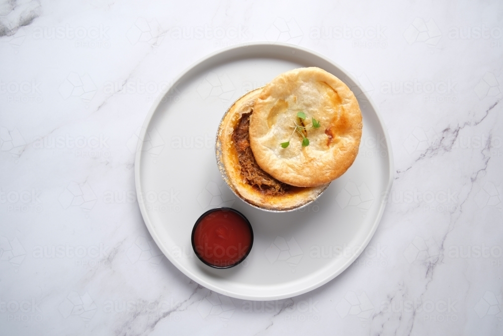 Small open meat pie with side of tomato sauce - Australian Stock Image
