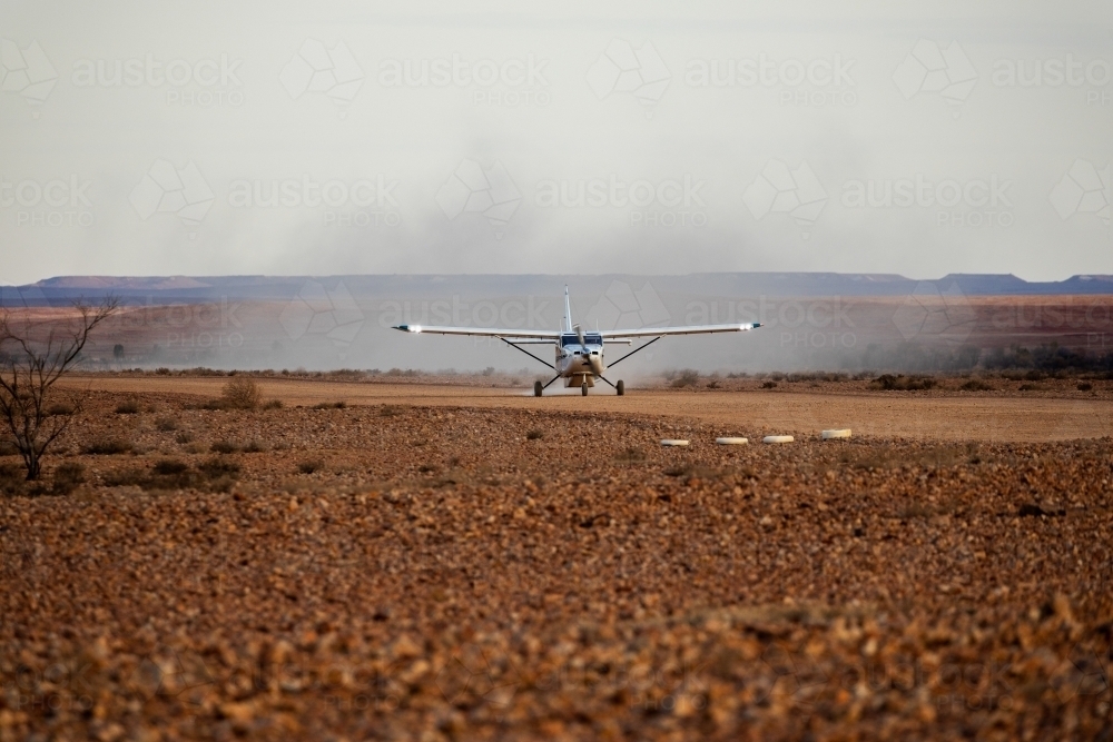 small plane landing on dirt airstrip - Australian Stock Image