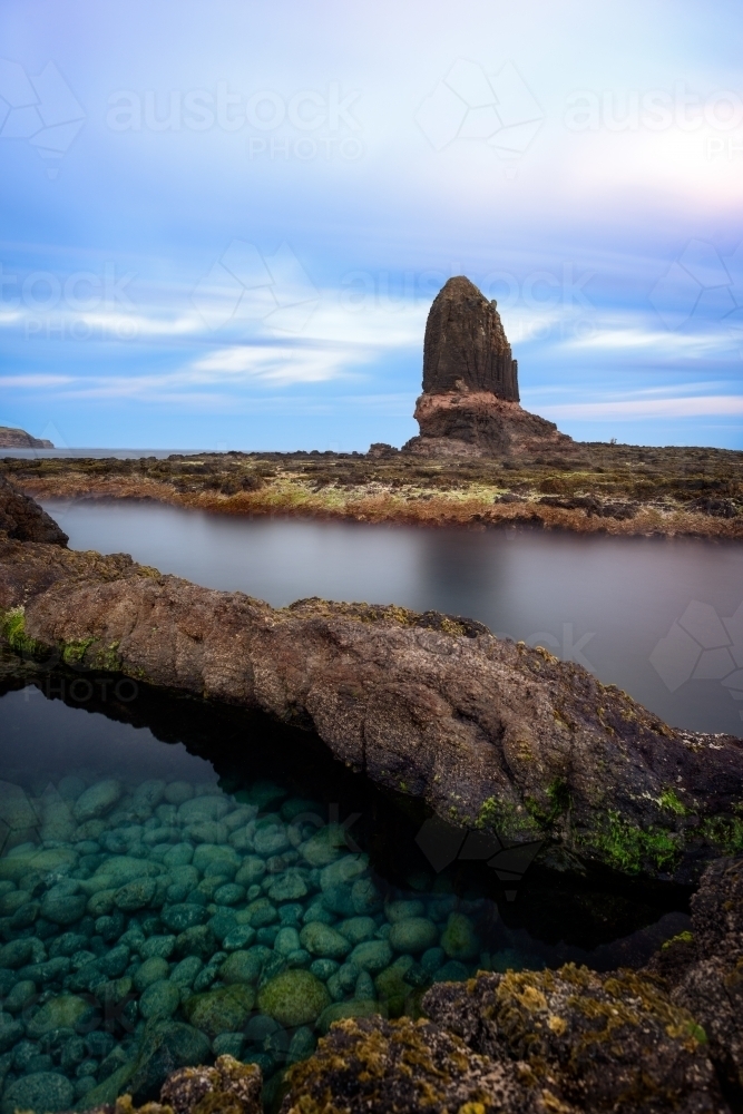 Small rock pool with rock structure in background - Australian Stock Image