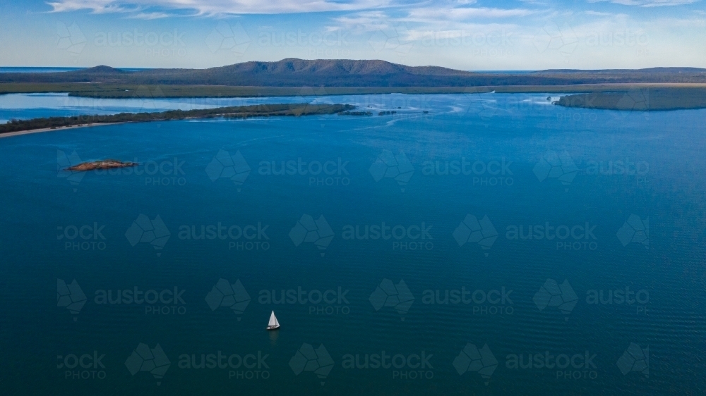 Small sailing boat in vast seascape between Bird Island and Turkey Beach, Queensland - Australian Stock Image