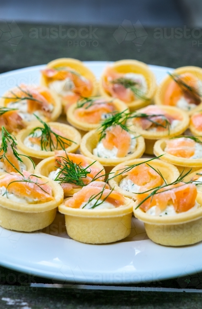 Small smoked salmon and dill tarts on a plate - Australian Stock Image