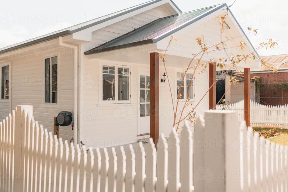 Small white house surrounded by picket fence - Australian Stock Image