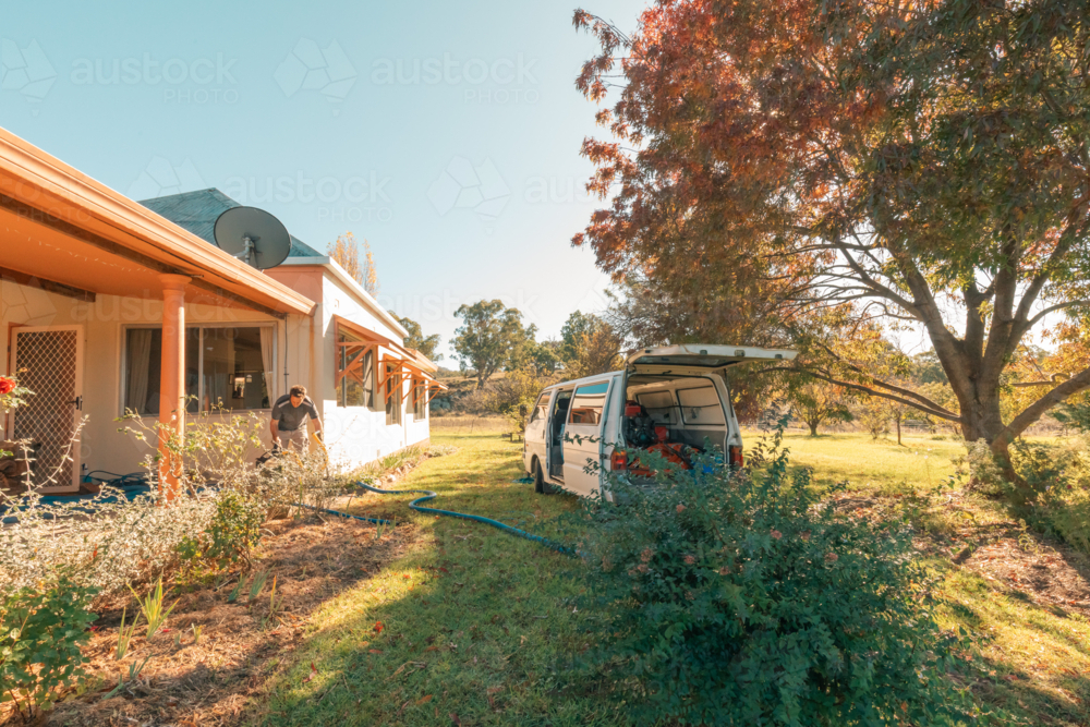 Small white van with commercial carpet steam cleaning equipment parked outside home with hoses - Australian Stock Image