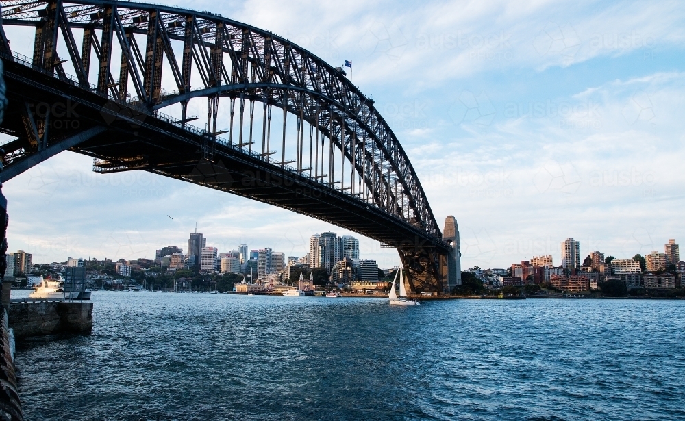 small yacht sailing under Sydney Harbour Bridge - Australian Stock Image