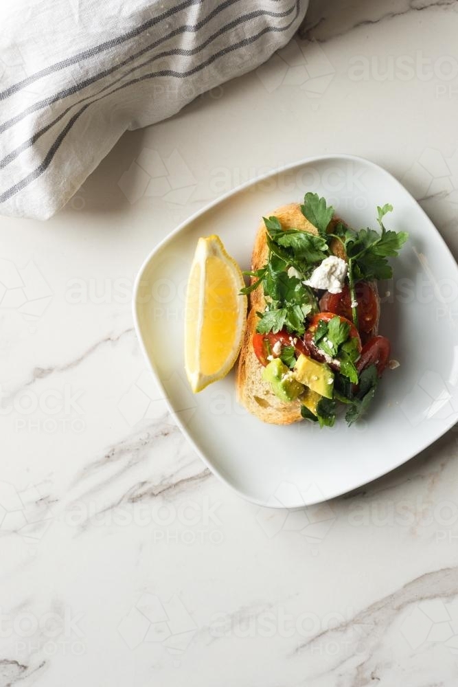 smashed avo on toast, with feta, tomatoes, parsley and lemon - Australian Stock Image