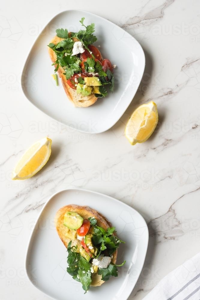 smashed avo on toast, with feta, tomatoes, parsley and lemon - Australian Stock Image