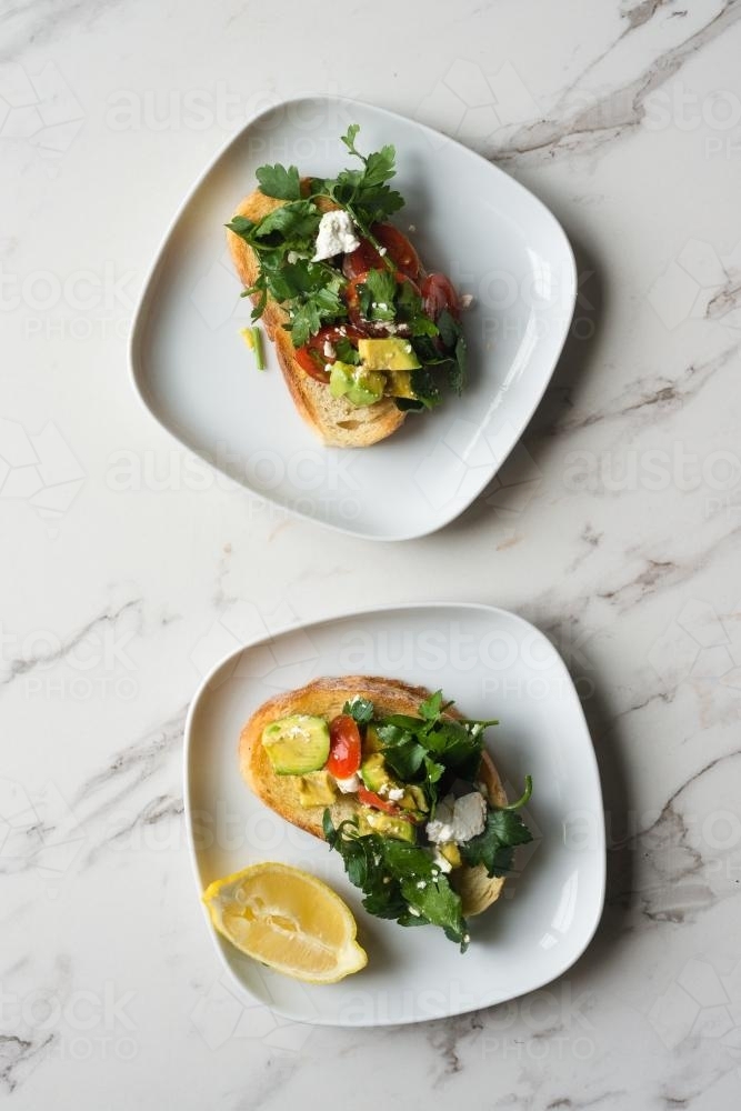 smashed avo on toast, with feta, tomatoes, parsley and lemon - Australian Stock Image