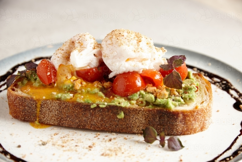 smashed avocado toast with tomato and poached eggs - Australian Stock Image
