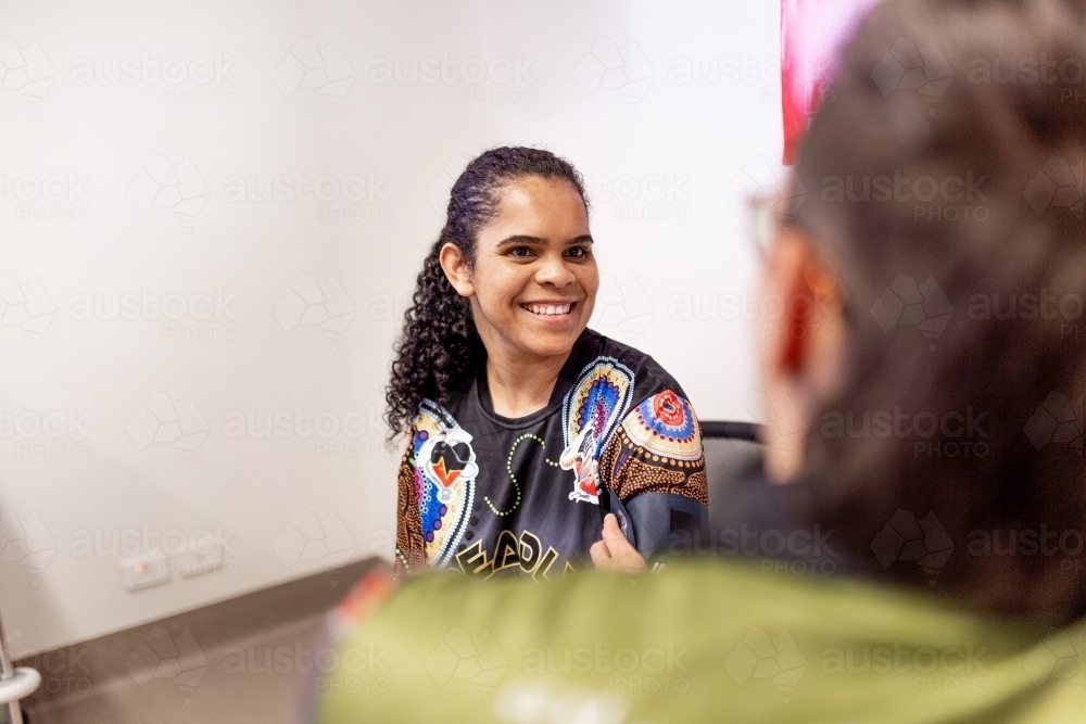 Smiling Aboriginal woman in a medical consultation with her doctor - Australian Stock Image