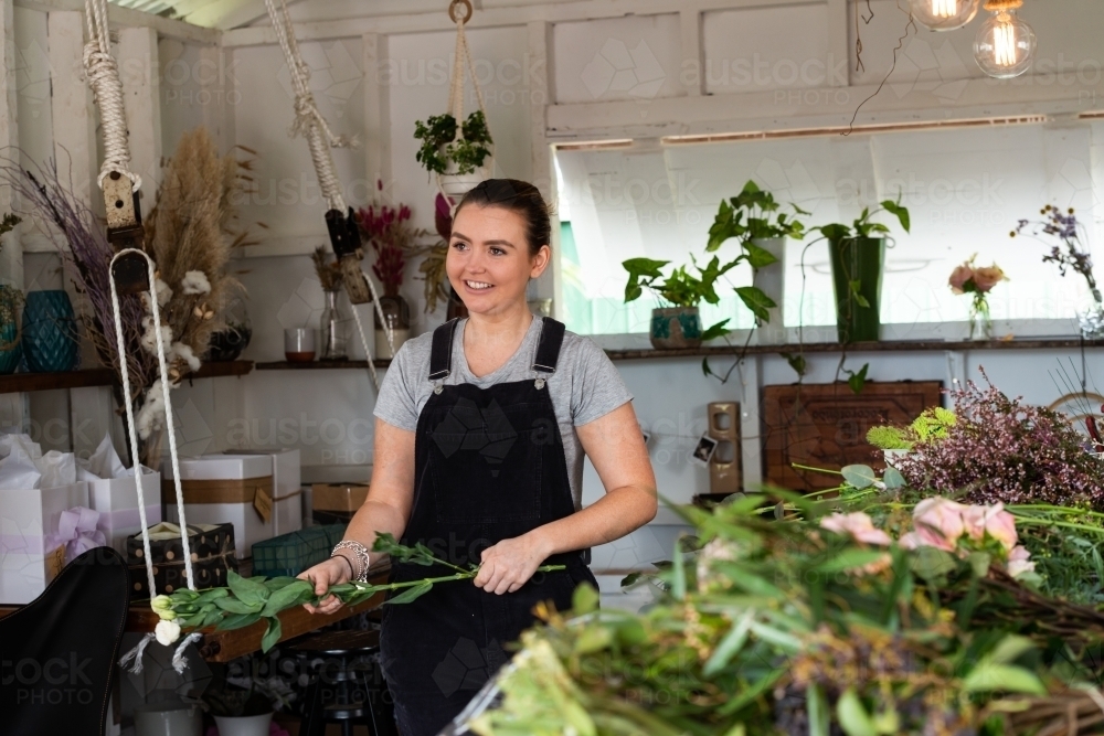 Smiling attractive young woman at work preparing flowers for an event - Australian Stock Image