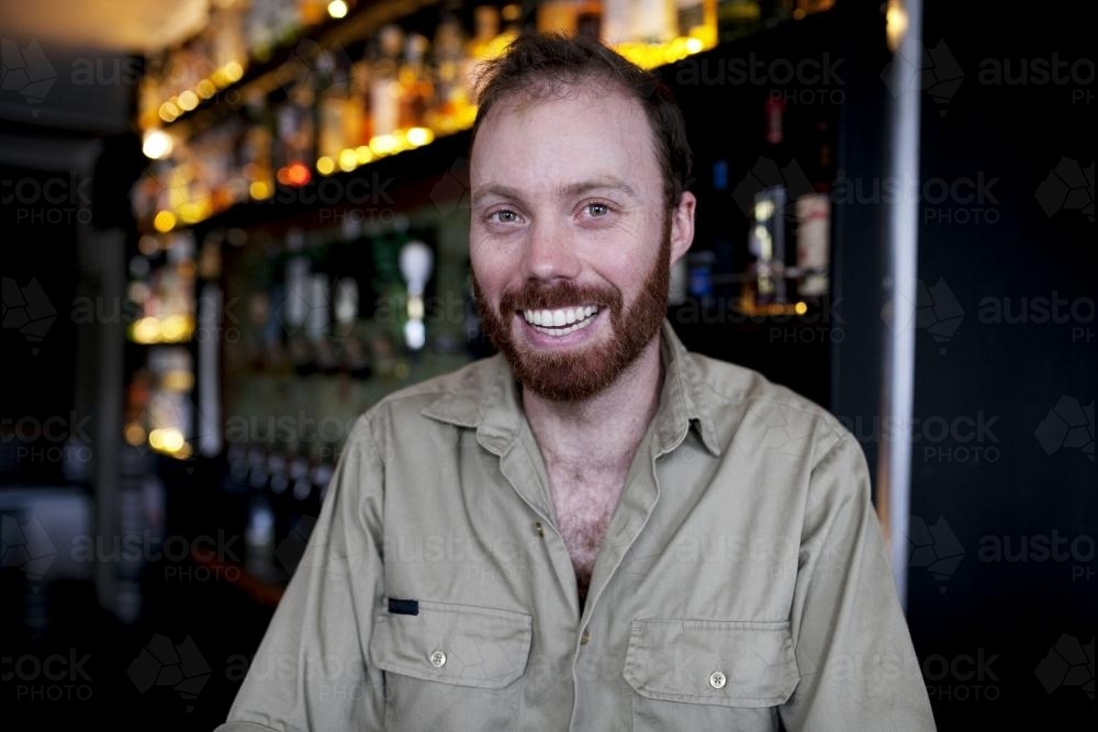 Smiling bartender behind the bar at local craft beer pub - Australian Stock Image