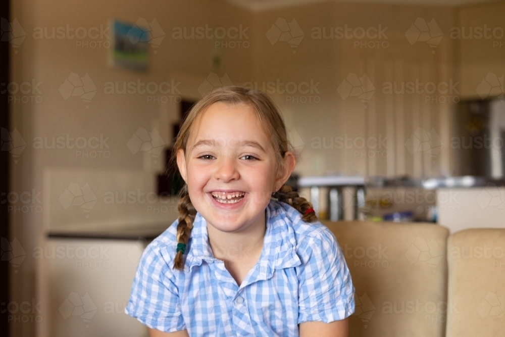 smiling child at home looking at camera with toothy smile - Australian Stock Image
