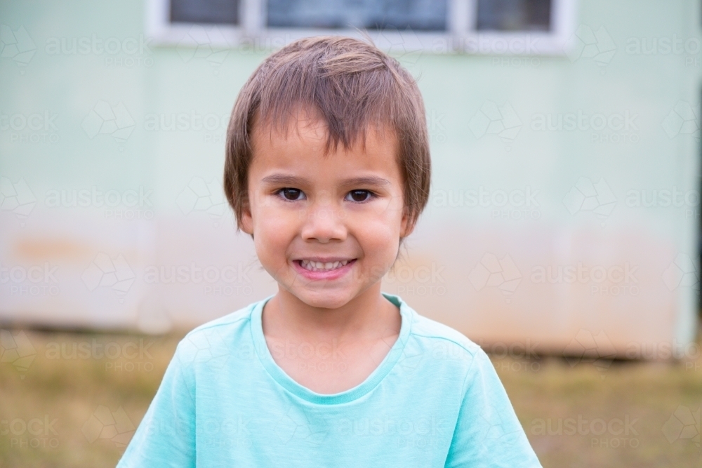 Smiling child outside home - Australian Stock Image