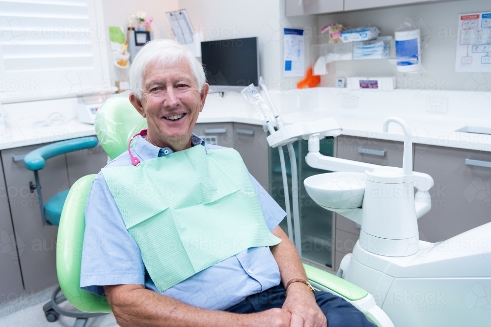 Smiling elderly male patient in dental office - Australian Stock Image