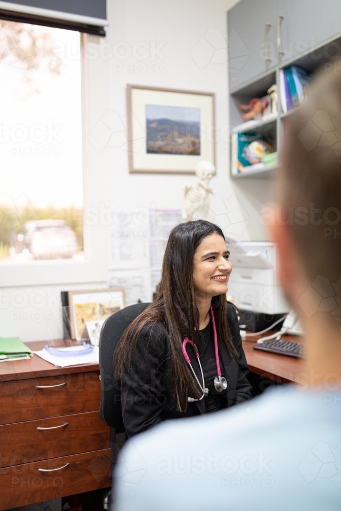 smiling female doctor sitting on the chair with stethoscope around her neck - Australian Stock Image