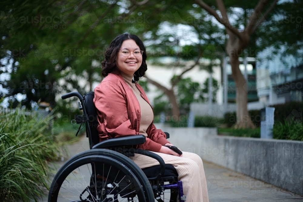 Smiling Filipina woman in wheelchair outside - Australian Stock Image