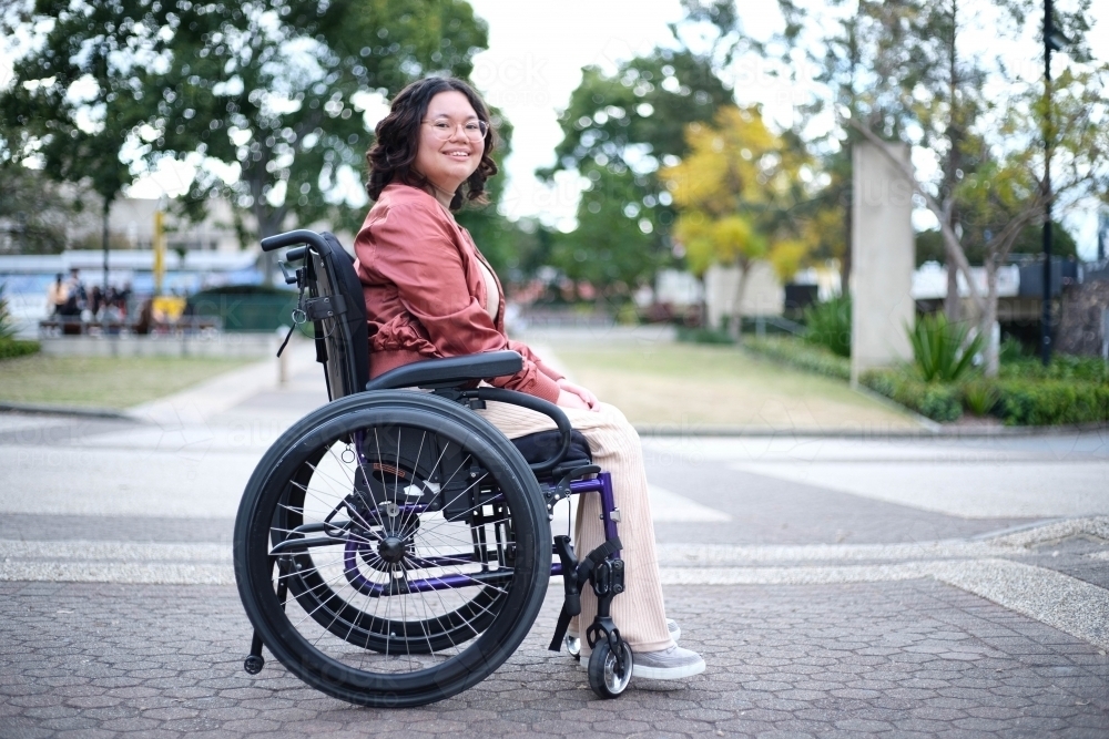 Smiling Filipina woman in wheelchair outside - Australian Stock Image
