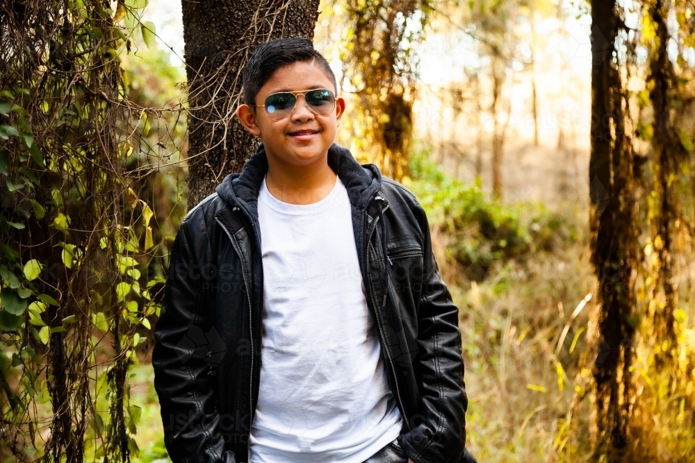 Smiling Filipino boy with jacket and sunglasses outside - Australian Stock Image