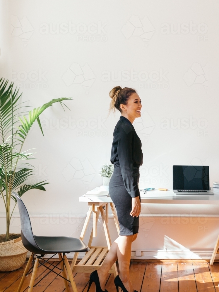 Smiling girl at work standing in an office looking off camera - Australian Stock Image