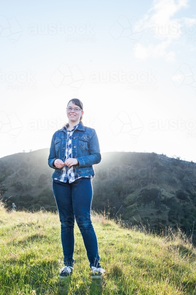 Smiling girl backlit by mountain sunrise - Australian Stock Image
