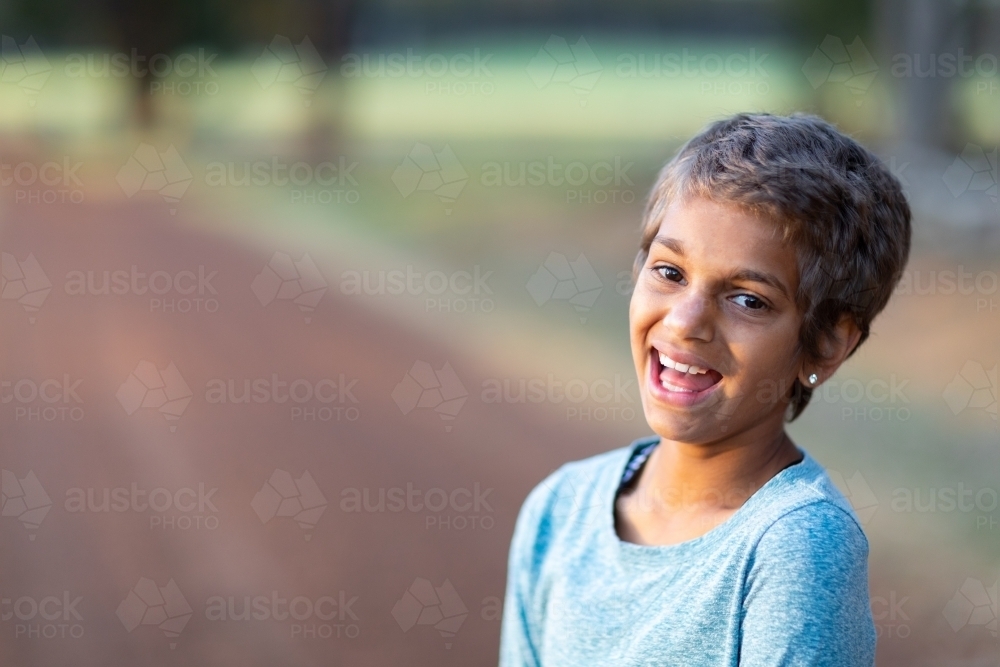 smiling happy child outdoors with blurred background - Australian Stock Image