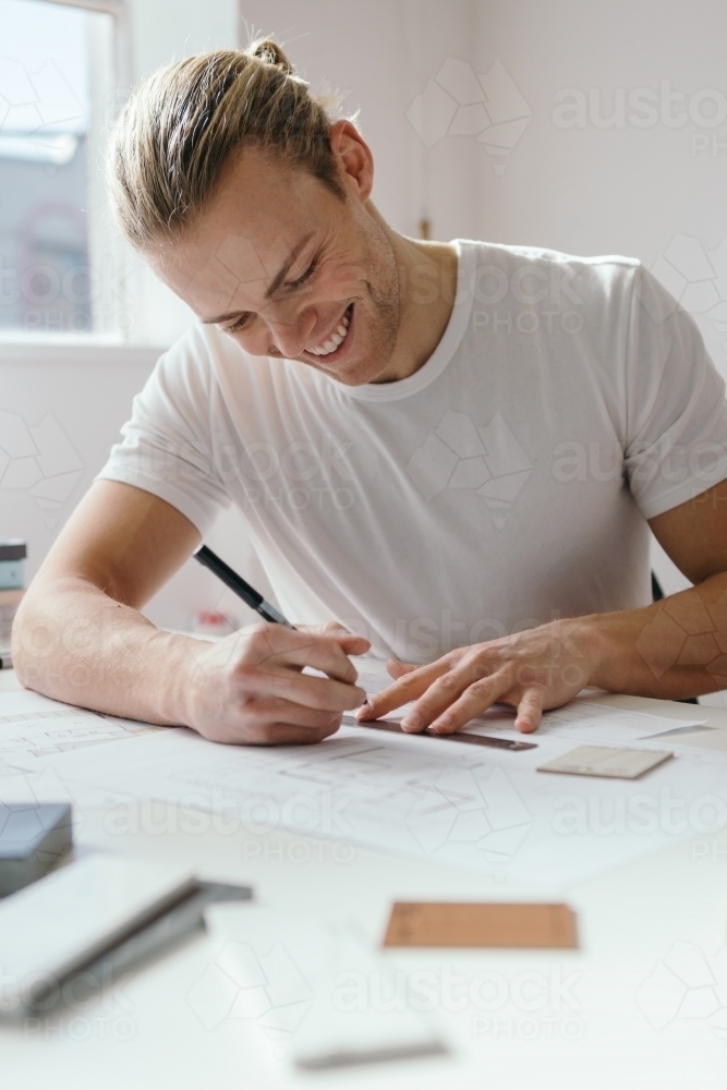 Smiling happy guy creating an architectural drawing - Australian Stock Image