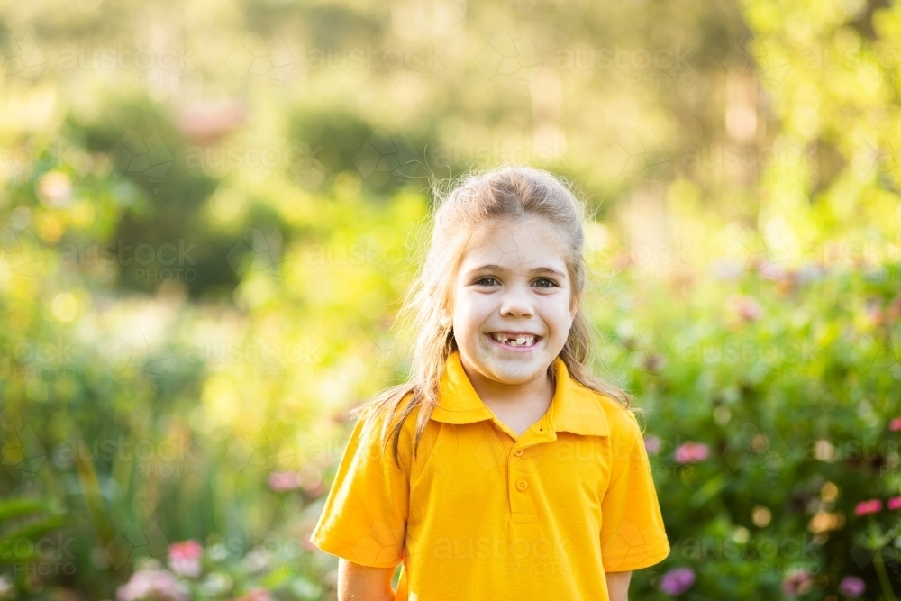 Image of Smiling happy school girl outside in yellow polo shirt ...