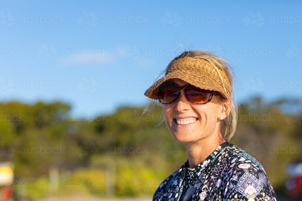 smiling lady with sun visor and sunglasses - Australian Stock Image