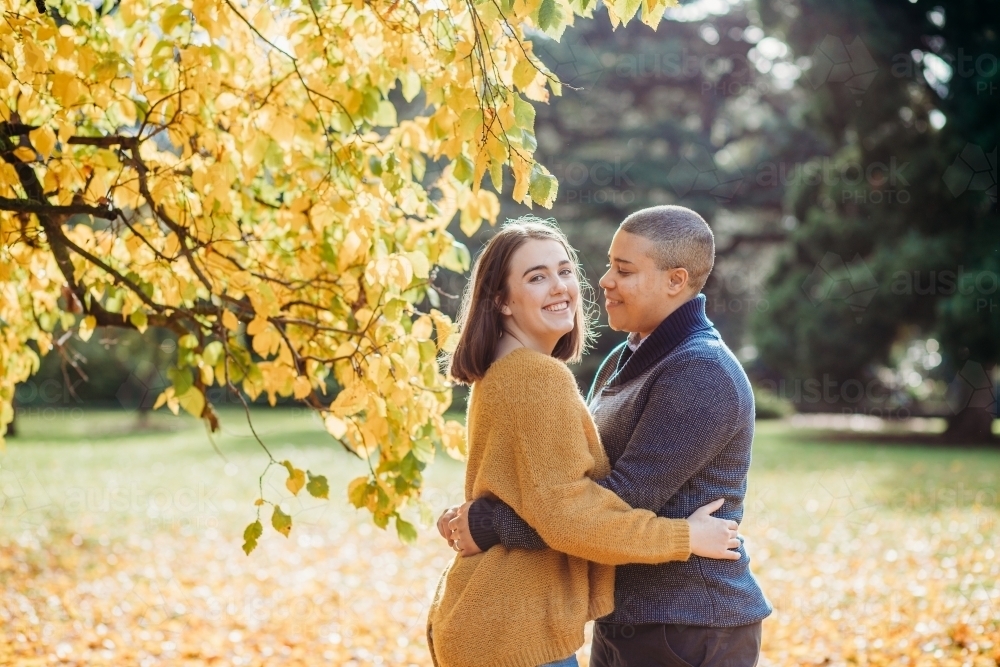 smiling lgbtqi couple hugging each other by autumn trees - Australian Stock Image