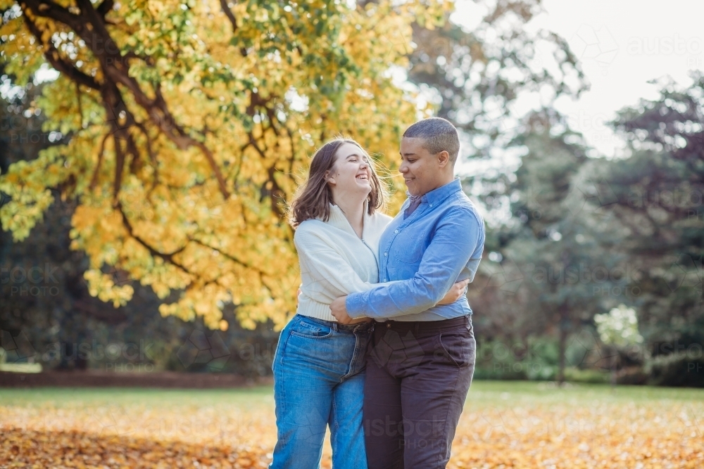 smiling lgbtqi couple hugging near autumn trees - Australian Stock Image