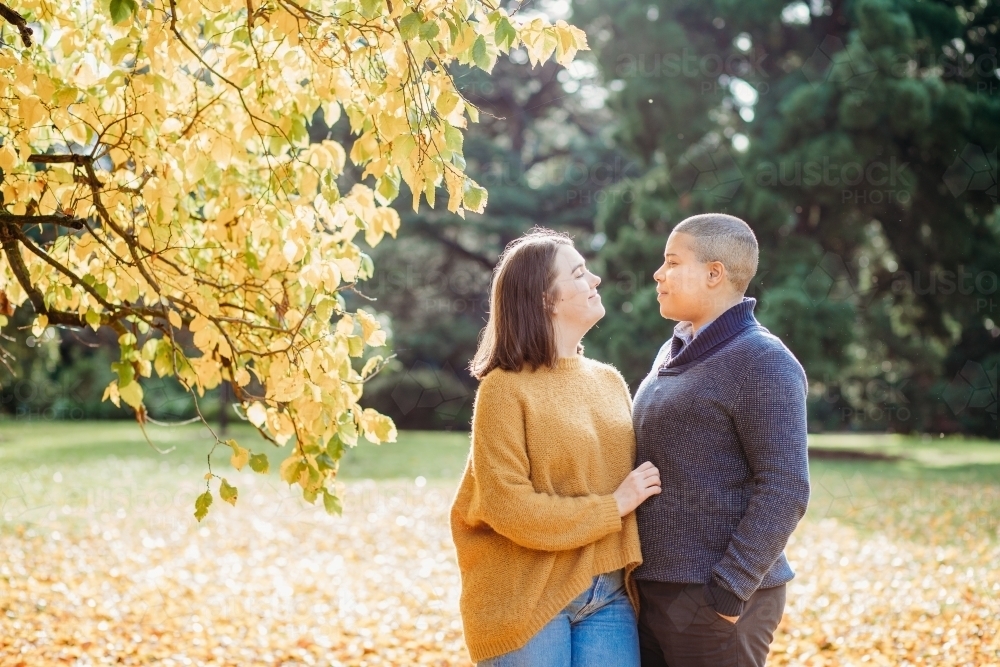 smiling lgbtqi couple looking at each other near autumn trees - Australian Stock Image