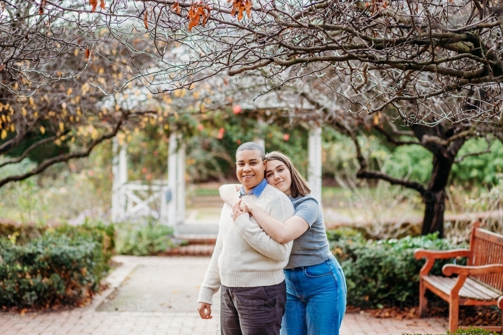 Smiling lgbtqi couple with one hugging the other - Australian Stock Image