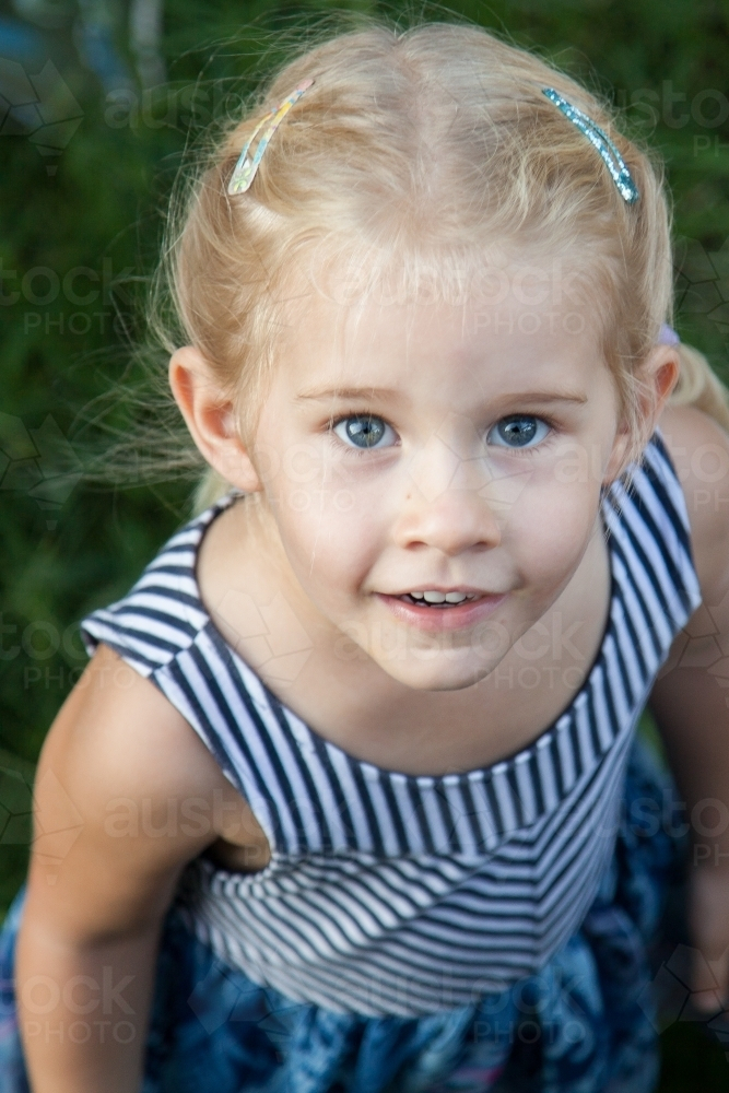 Smiling little girl looking up in portrait - Australian Stock Image