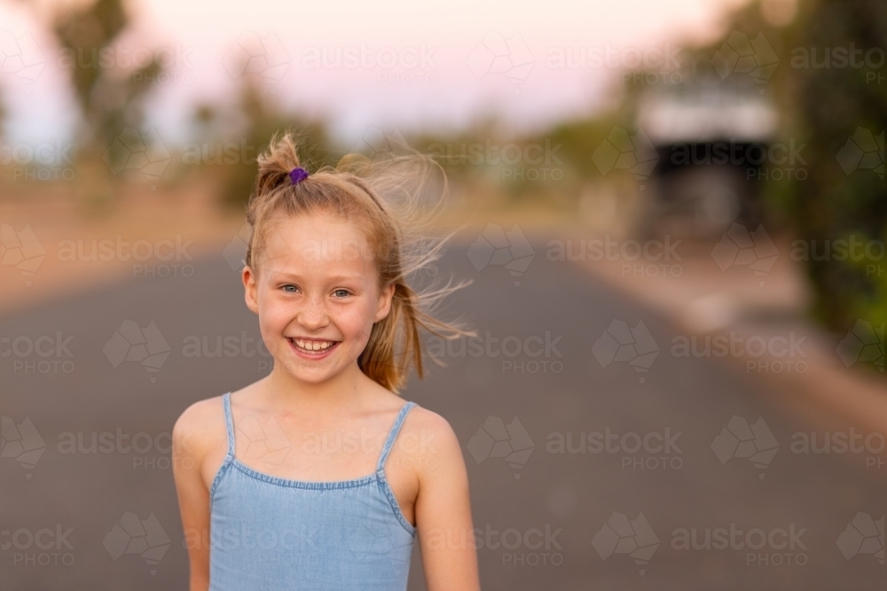 smiling little girl outside by herself in the evening - Australian Stock Image