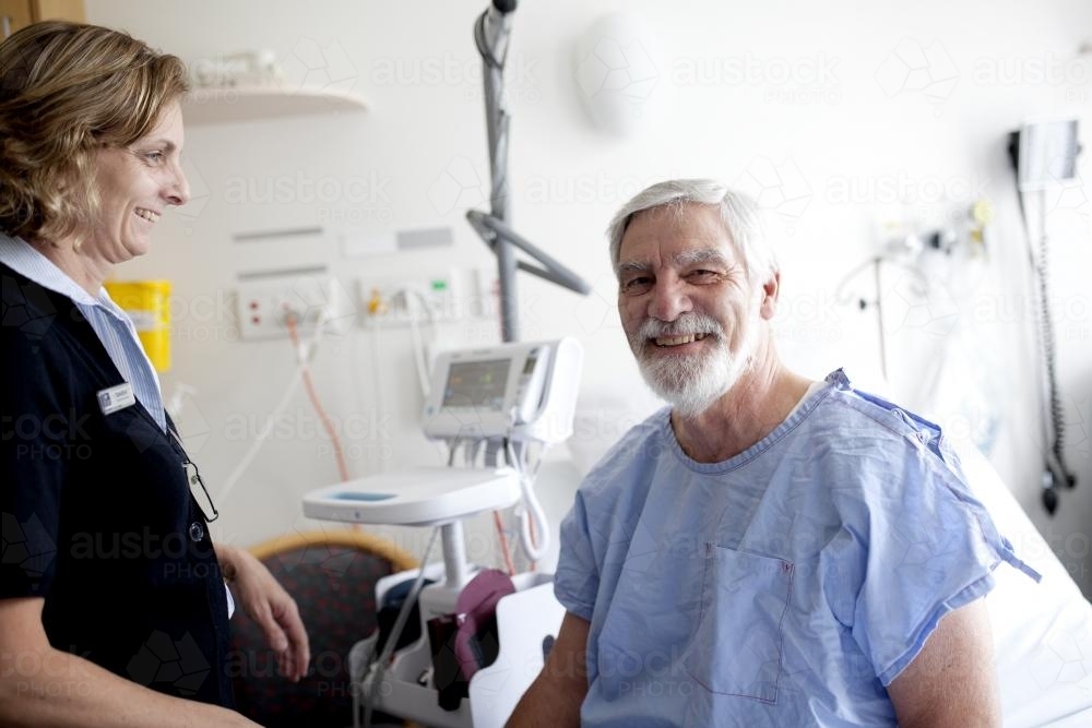 Smiling middle aged male patient being treated by a nurse in a hospital ward - Australian Stock Image