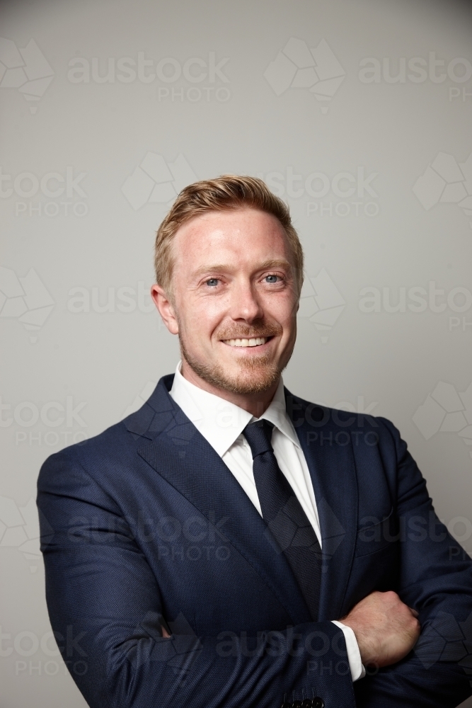 Smiling middle aged man wearing suit and tie with arms crossed - Australian Stock Image