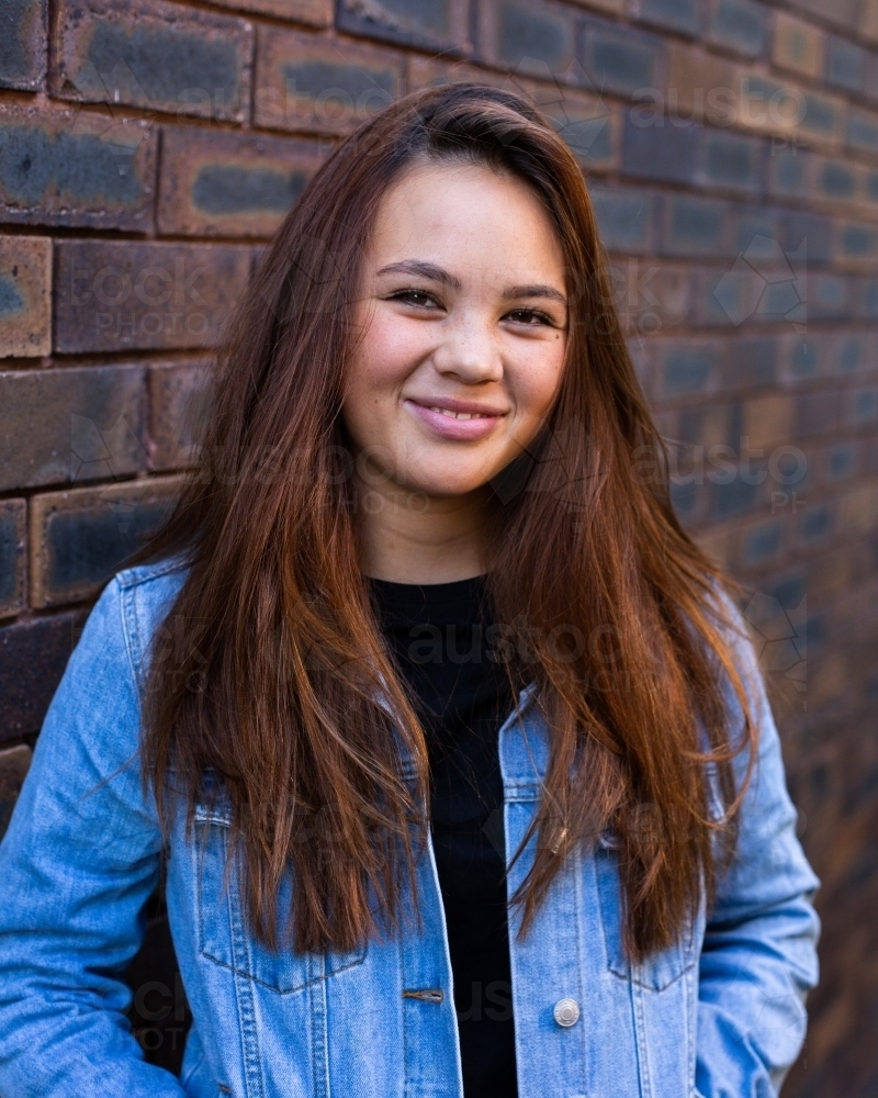 smiling mixed race teen girl in a denim jacket - Australian Stock Image