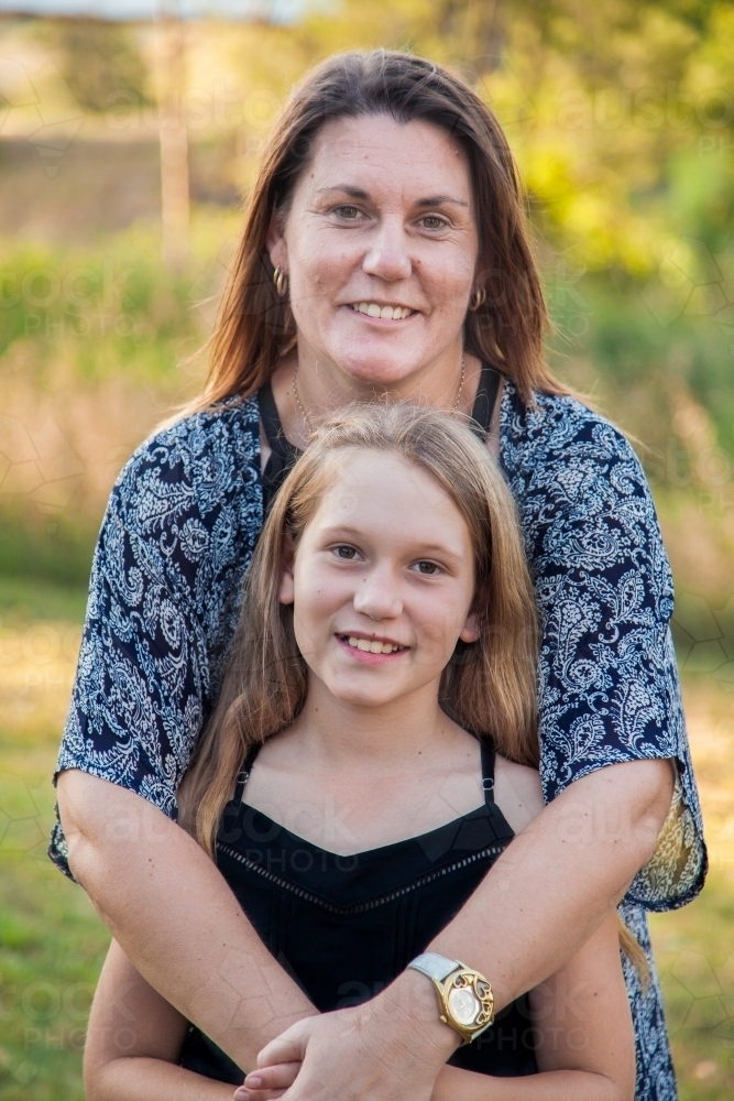 Smiling mother and daughter portrait mother hugging tween daughter - Australian Stock Image