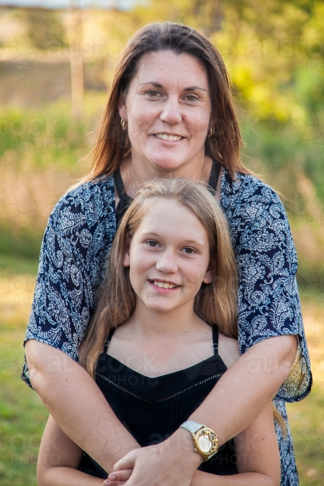 Smiling mother and daughter portrait mother hugging tween daughter - Australian Stock Image