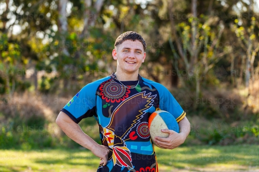 Smiling portrait of happy young aboriginal sports player with ball - Australian Stock Image