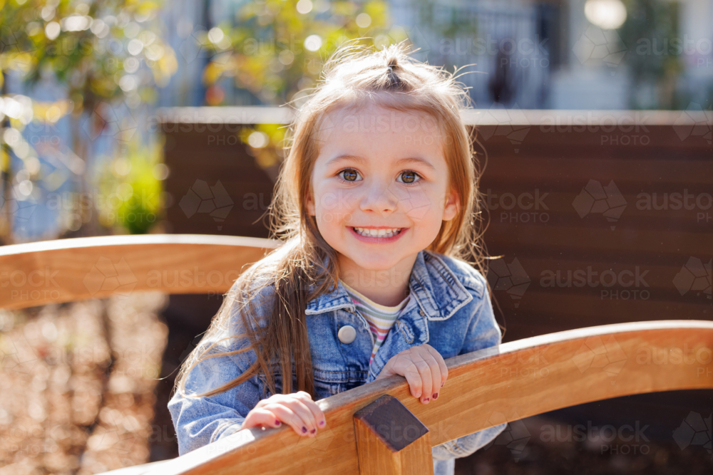 Smiling preschool child on wooden bridge in kindergarten yard - Australian Stock Image